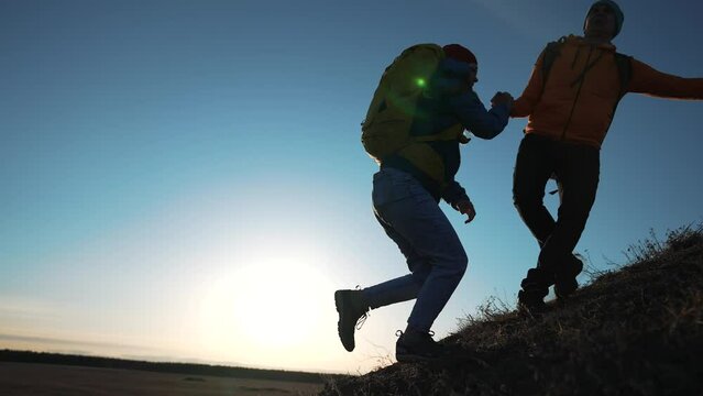 Successful business concept. man and woman together in mountains at sunset. teamwork. business and achieving goal together. success and help in the team. helping hand to achieve goal. joint success