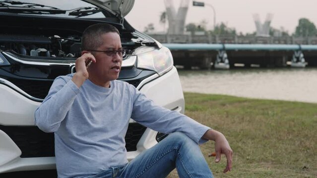 elderly man uses the phone to talk to his insurance and request emergency services when his car is in an accident.