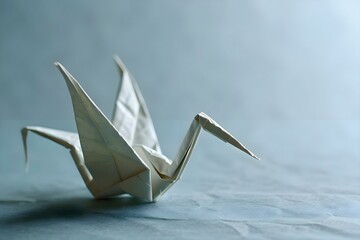 a white origami bird sitting on top of a table - obrazy, fototapety, plakaty