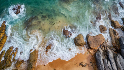Naklejka premium Aerial view top seashore, rocky coast, waves crashing on rock cliff. Blue ocean surface sunny summer