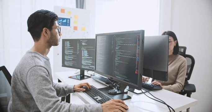 Young adult Asian male, female software developer coding program on desktop computer. Man, woman work from home, remote working, freelance programmer job, smart digital nomad lifestyle concept