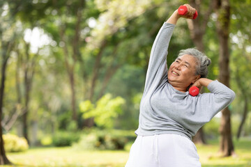asian elderly woman exercising and lifting dumbbells in the park