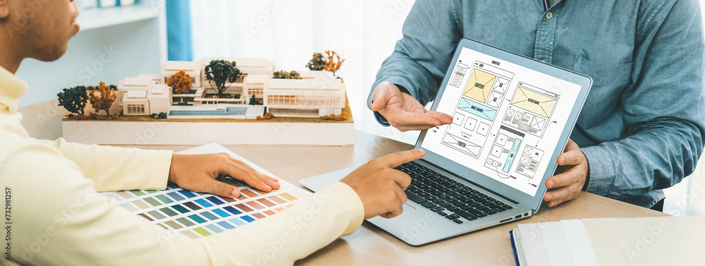 Poster cropped image of interior designer presents color from color swatches while laptop displayed website