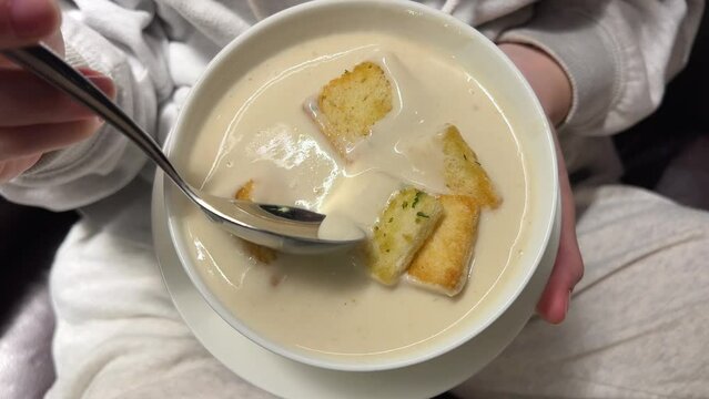close-up cheese soup in a bowl with croutons, girl stirs soup with a spoon. slow motion. High quality 4k footage
