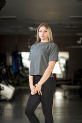 Fototapeta na wymiar A beautiful young girl is working out in the gym in sportswear.