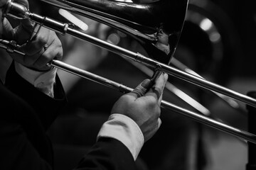  A fragment of a trombone in the hands of a musician close-up in black and white