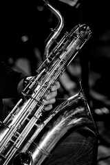 Baritone saxophone in the hands of a musician close-up in black and white