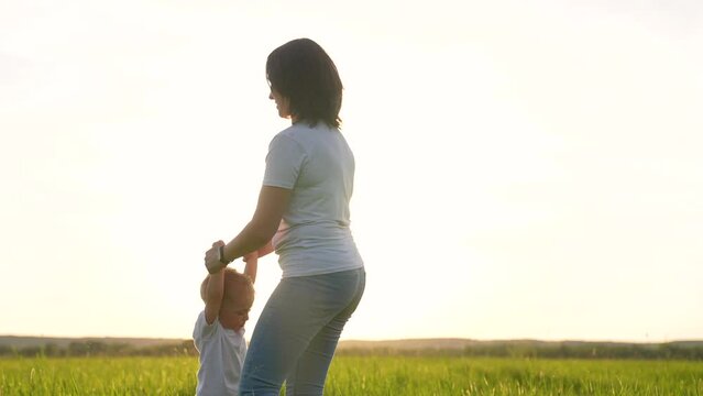 Happy family concept. family portrait of mother and baby at sunset. active family recreation outdoors in forest park. the mother lifts child into the air and spins around.mother and baby holding hands