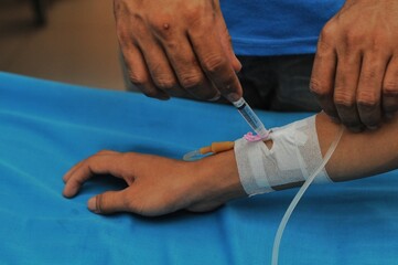 a paramedic's hand injects medication into a patient who is being given an IV drip