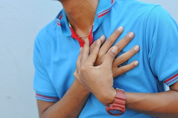 hand hold chest with heart attack symptoms, asian man have chest pain caused by heart disease, leak, dilatation, enlarged coronary heart, press on the chest with a painful expression