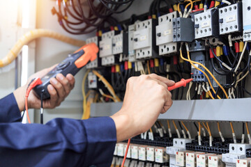 Electrician measurements with multimeter testing current electric in control panel.	