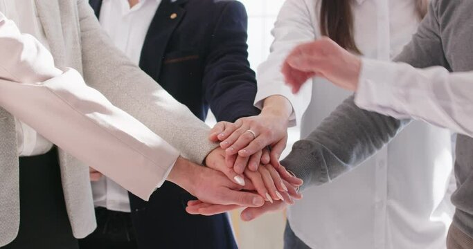 Close up of business people putting their arms together. Stack of hands of a group of company employees in office. The concept of unity, partnership and teamwork. 4k video. Slow motion video.