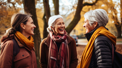 Fototapeta premium Cheerful senior women looking at each other while walking in autumn park