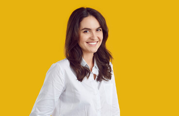 Portrait of smiling young shy modest brunette woman office worker in white shirt is posing on...