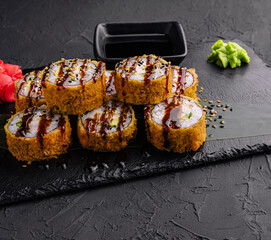 Warm sushi with ginger and wasabi served on a black stone plate