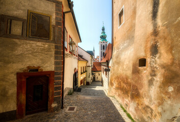 Fototapeta na wymiar Alley in Beautiful Cesky Krumlov in the Czech Republic, with the Tower of St Jost Church