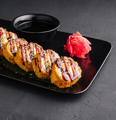 Served warm sushi with ginger and wasabi on a black stone plate