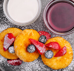 Cottage cheese pancakes with Berries, Powdered Sugar, Jam, and Sour Cream on Black Plate