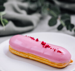 Eclairs with pink glaze on a white plate
