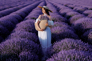 .Woman in a field of lavender flowers at sunset  holding lavender flowers. France, Provence.