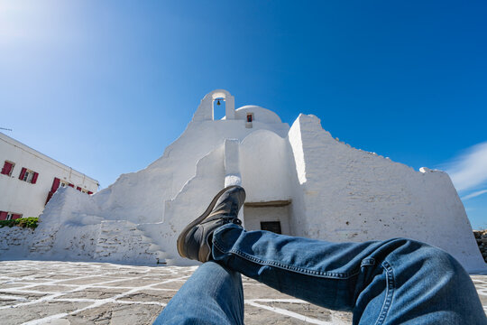 Concept of male tourist relaxing on holiday in front ofAncient Paraportiani Church in Mykonos Town. Greece