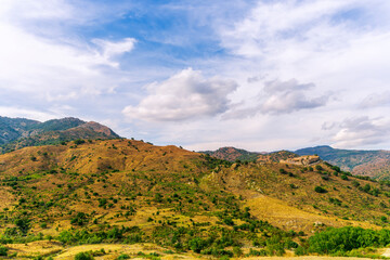 amazing view of green and yellow mountains with blue cloudy sky on background,