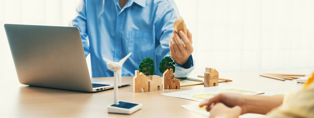 Two business people talking about eco city at green business meeting on meeting table with windmill...