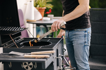 Close-up of man make a fire and controls the process. BBQ grill outdoor