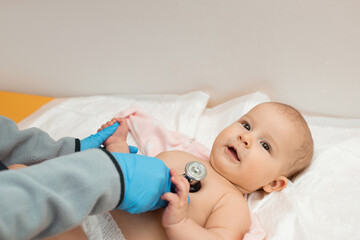Pediatrician examining baby girl. A doctor uses a stethoscope to listen to a child's heartbeat. Close up. 