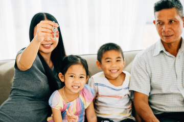 A joyful family mother holding new house keys poses for a portrait with children and dad....