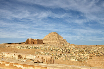 Obraz premium View of the step pyramid of Djoser together with some dummy buildings inside the complex, under dramatic blue sky - Saqqara, Egypt