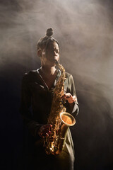 Vertical portrait of elegant Black woman playing jazz music on stage in nightclub in moody setting...