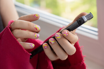 Stylish summer colorful nails female manicured hands holding mobile phone. Closeup of manicured...