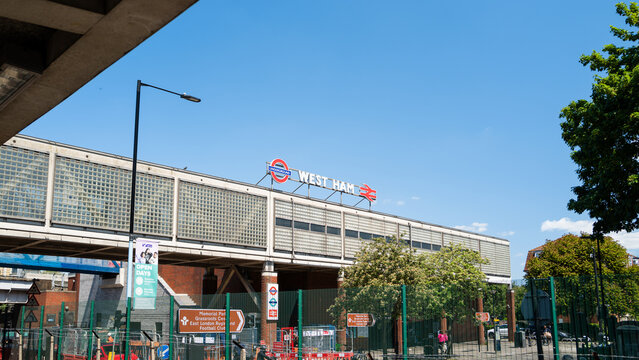 London, UK - June 10 2023 : Detail signage West Ham station with signage for train and subway on bright sunny day, blue sky. Travel destination in the city for football, residential, food and drink.