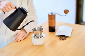 キッチンでコーヒーを淹れる若い女性