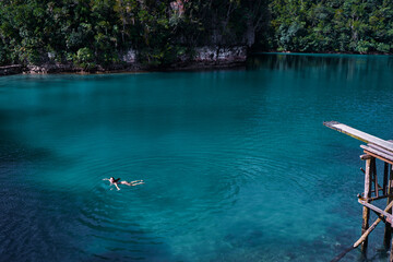 Vacation and activity. Young woman in swimsuit swimming in blue tropical lagoon. Siargao Island, Philippines.