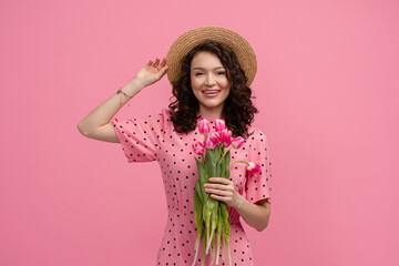 pretty young woman posing isolated on pink studio background with tulips flowers