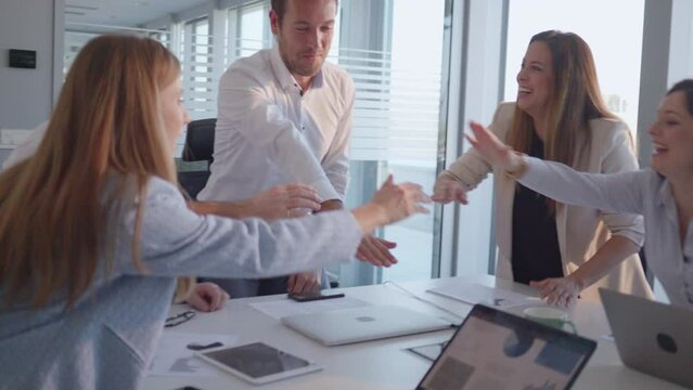 Happy businesspeople team celebrating success with applause in corporate meeting. Smiling employees standing together, showing unity and teamwork slow motion handheld shot