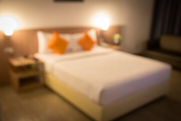 Blurred image of a hotel bedroom with 2 orange pillows, modern and minimalist decor. The bed is soft, clean, good atmosphere