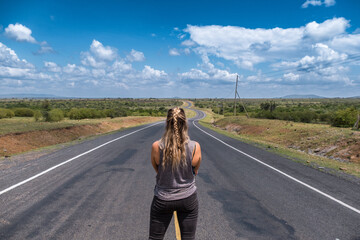 Solo female traveller on road trip standing in road
