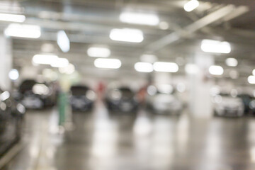 Blurred image of many cars parked in the parking lot under the building to go shopping in the mall which has a good care of safety bright parking There is a CCTV box recording.