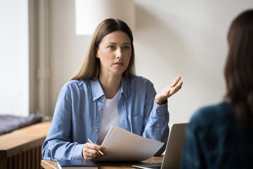 Serious company leader woman in informal shirt interviewing job candidate, talking to female...