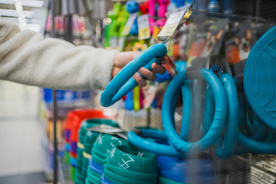 Close-up of a customer's hand examining a blue dog play ring in the animal toy department. Pet owner chooses a toy for his beloved dog in the supermarket