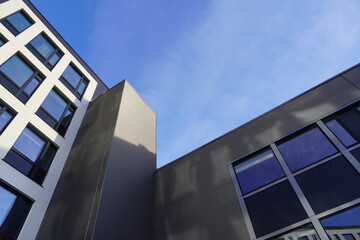 Look up to white and grey building facade towards blue sky. Kopli, Tallinn, Estonia. February 2024