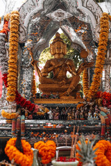 Golden statue of the Thai god with orange fresh flowers. Thai tradition