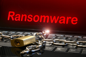 Computer security concept with an iron chain and padlock on the laptop keyboard and "Ransomware" text on the screen. Cyber threat concept image.
