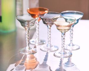 Crystal colorful stemware set with reflection on a table. Colourful elite set of empty alcohol liquor glasses on white, border design. Stemmed glasses, drinkware closeup 