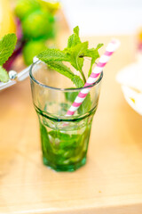Glass of cold water and fresh mint with stripped strokes standing on table