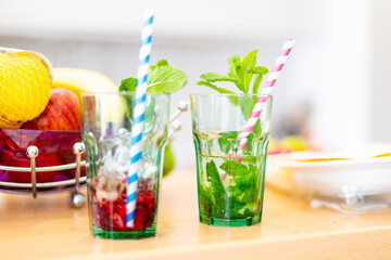 Glasses of cold mint refreshment with stripped strokes standing on table