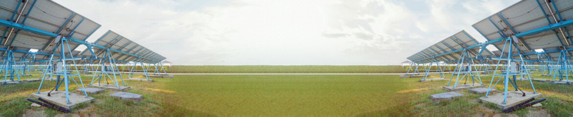 Panoramic view of solar farm with photovoltaic panels arranged in rows on green field under cloudy...